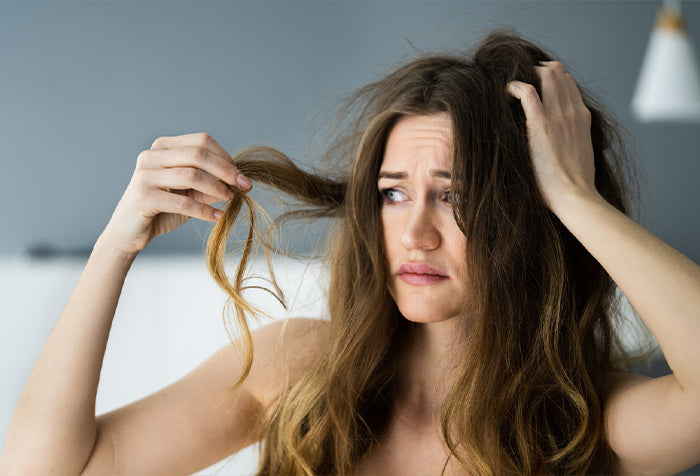 Older woman examining her hair with a stressed out demeanor.