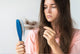 woman holding stands of her hair stuck on the hair brush