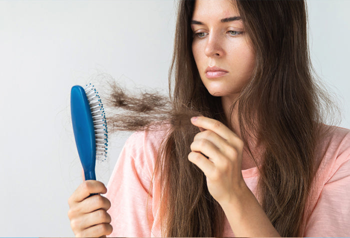 woman holding stands of her hair stuck on the hair brush