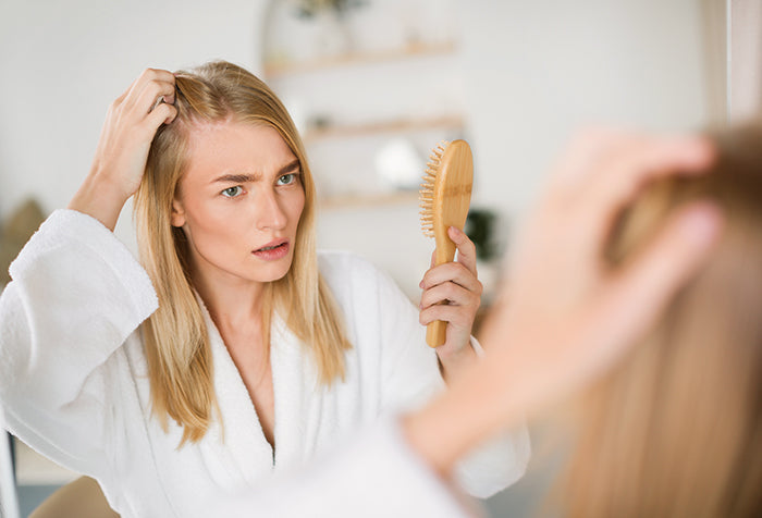 Woman examining her hair line.