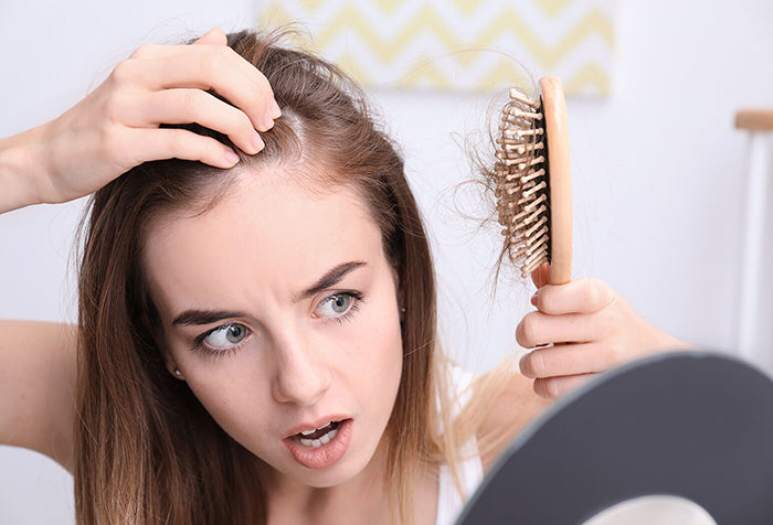 Young woman examining hair in her comb.